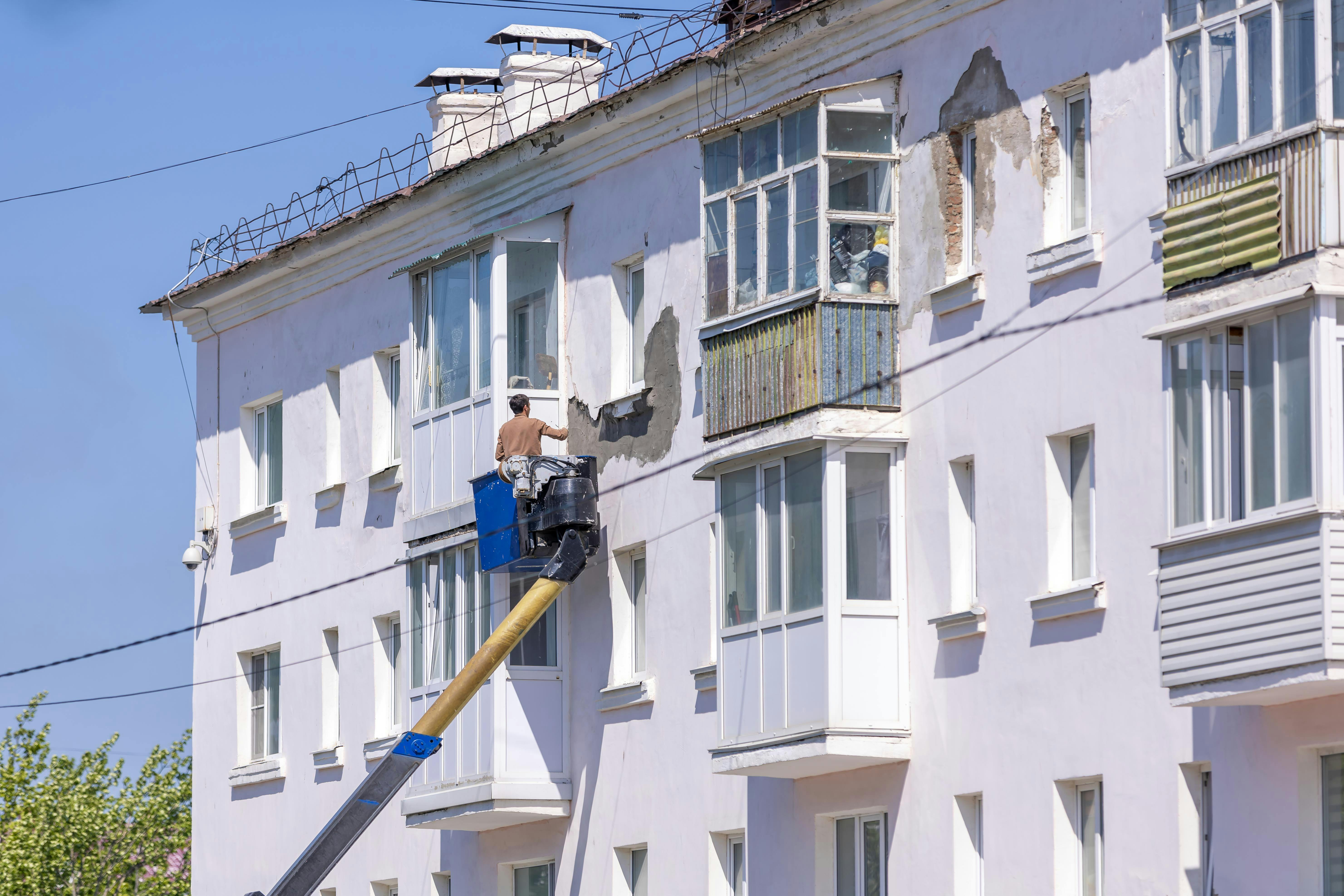 Exterior%20stucco%20repair%20with%20cherry-picker Trusted contractors working on the exterior of a rental